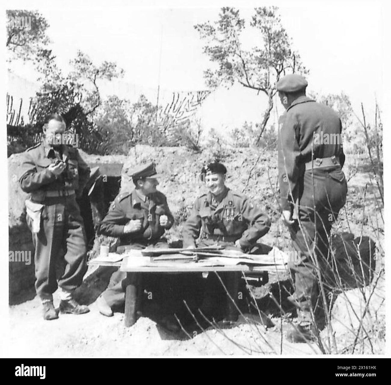 ALLIED ARMIES IN THE ITALIAN CAMPAIGN, 1943-1945 - General Władysław Anders, the CO of the 2nd Polish Corps (second from the right) and General Charles Keightley, the CO of the British 78th Infantry Division (second from the left) sitting outside General Keightley's dugout with maps and air recce photos. They are accompanied by Brigadier Thrith (far left) and Lieutenant Eugeniusz Lubomirski, General Anders' adjutant (far right).Photograph taken during General Anders' visit to the 78th Division at Cervaro (near Cassino) British Army, Polish Army, Polish Armed Forces in the West, Polish Corps, I Stock Photo