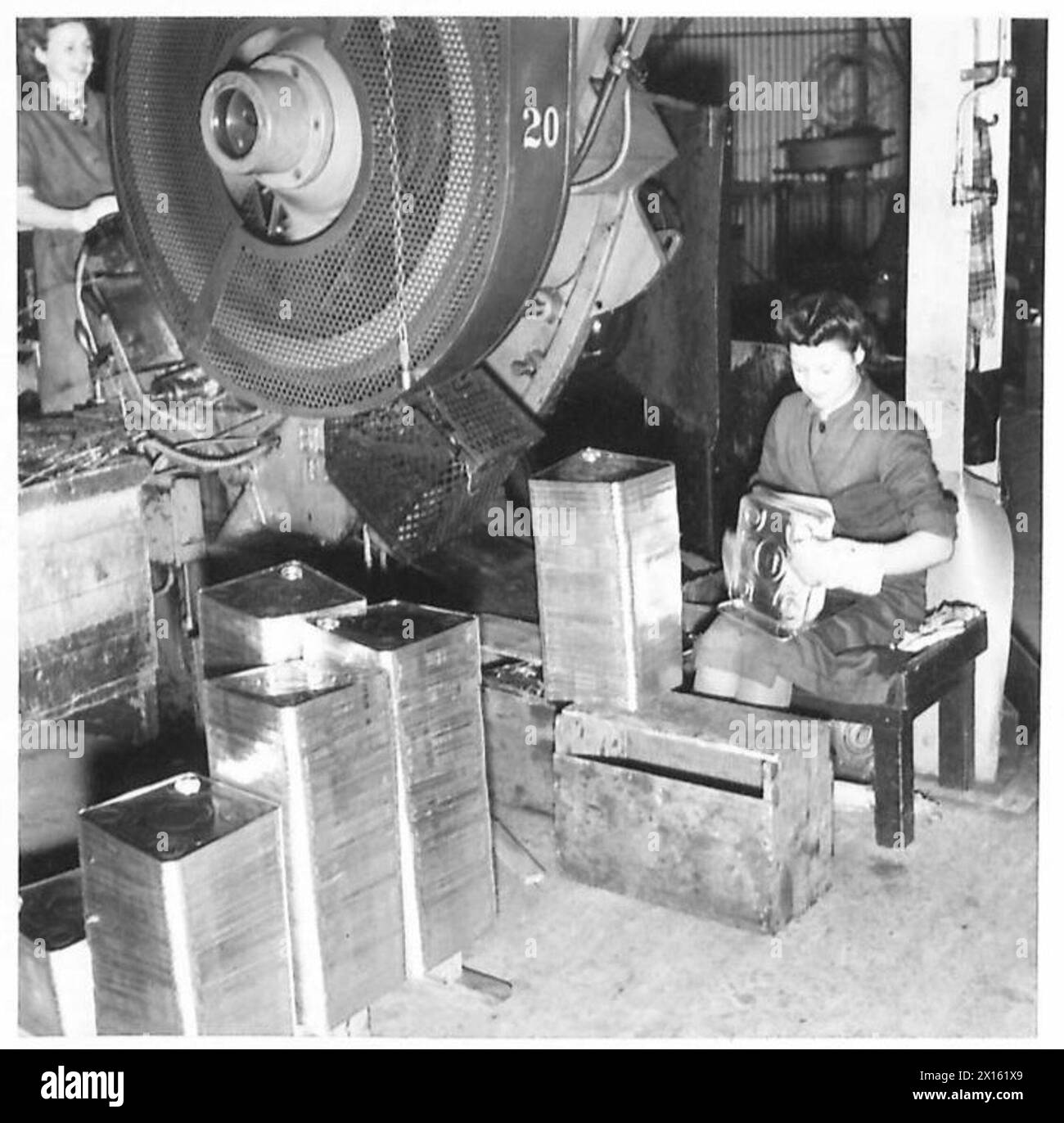 BASE PETROL FILLING DEPOT AT NEATH - The making of the tops and bottom of the tins is a separate operation. Here the tops and bottoms are seen leaving the machine which stamps, them out British Army Stock Photo