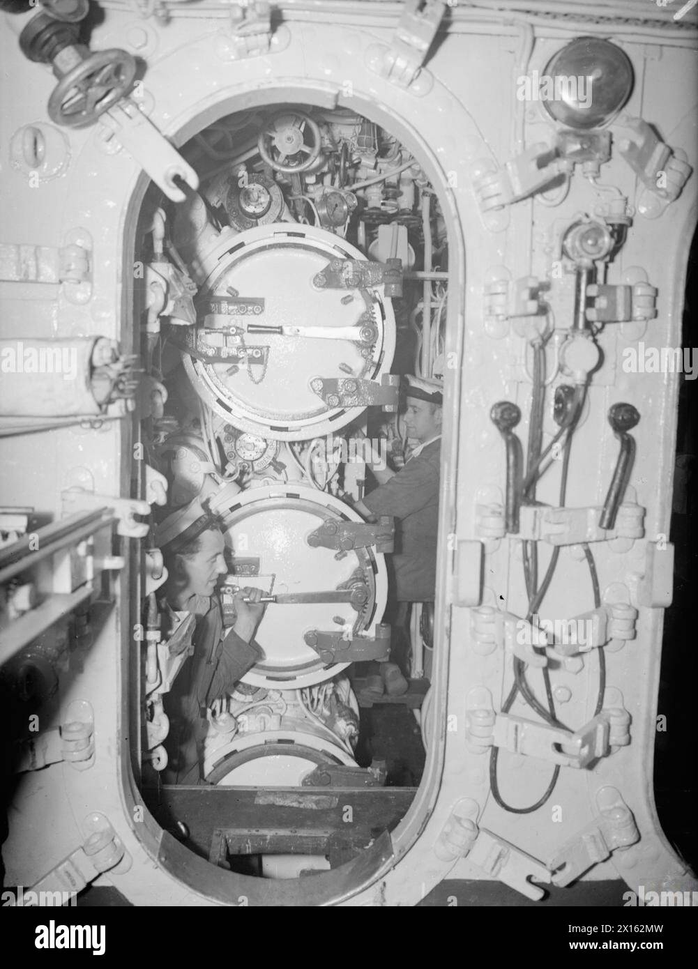 Crew members operate the three forward torpedo tubes aboard HMS Osiris ...