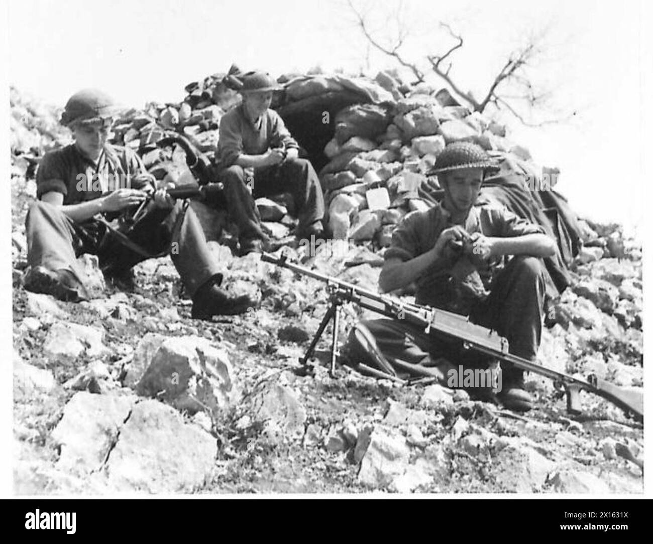 FIFTH ARMY AREA : VARIOUS - Men of 'CCompany holding positions on the ridge above the 'Bowl' come down to clean and overhaul their weapons before returning at night-time. They are:- (Right) Pte. B.A.F. Smith of 67 Beloe Crescent, King's Lynn, Norfolk (Left) Pte. W. Peacock, of Diss Road, Banham, Norfolk (Centre background) Pte. G.J. Moore, of 'Homestead' West Bradenham, Thetford, Norfolk British Army Stock Photo