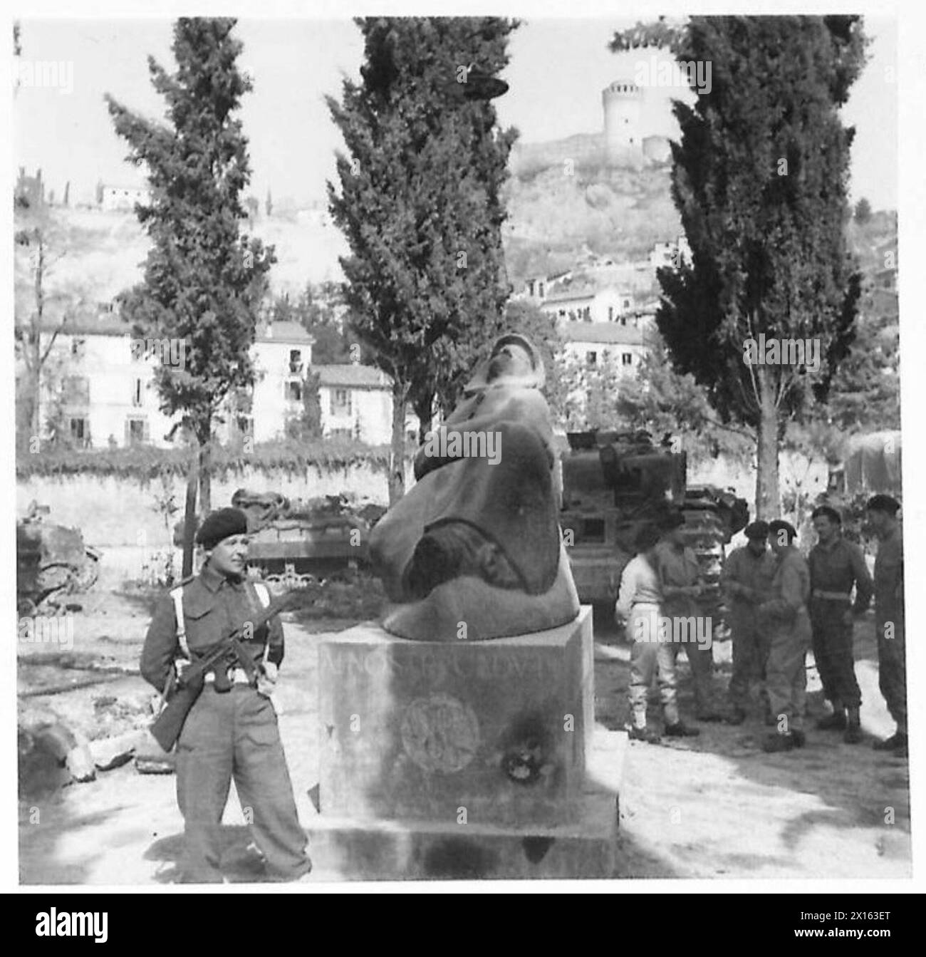 EIGHTH ARMY : VARIOUS - Tpr. William Parker of 16 Hampton-Dunscroft Road, Doncaster, Yorks, stands beside the War Memorial at Brisighella as he guards the tank park of 'A' Sqn. 8 Royal Tank Regiment. In the background is the ancient Castello Rocca Di Brisighella, built by the Venetians British Army Stock Photo