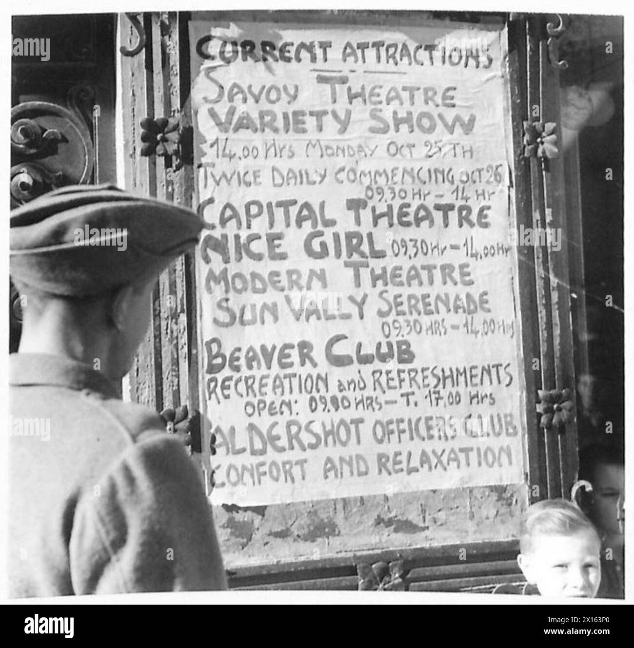 ITALY : EIGHTH ARMY ENTERTAINMENT TOWN - 'Current Attractions' A soldier reads the notice board of events … 'Savoy Theatre - Variety Show' 'Capital Theatre - Nee Girl' 'Modern Theatre - Sunvalley Serenade' 'Beaver Club' 'Aldershot Officers Club' , British Army Stock Photo