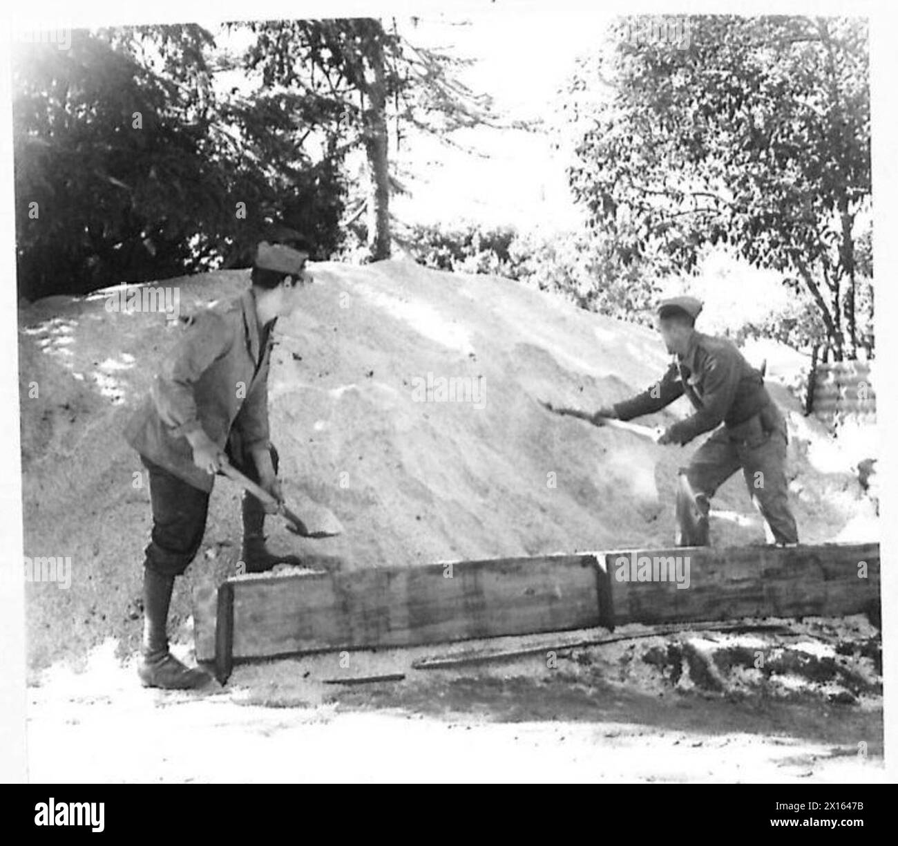 ITALY : EIGHTH ARMY ENTERTAINMENT TOWN - 8th Army prepared for the winter. An Italian and a British soldier work on a huge pile of salt, stored in an Engineer's dump near Campbbassa ready for frosty roads and corners. So scarce and highly prized is salt in Italy now that even this course salt has to be carefully guarded against civilian theft British Army Stock Photo