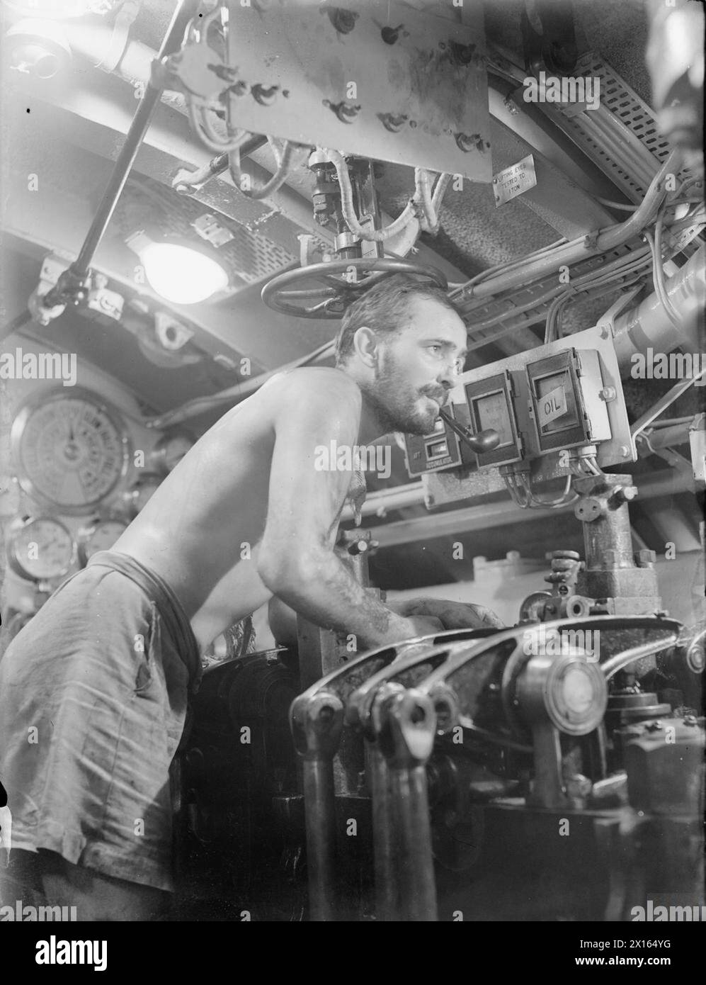 WITH THE EASTERN FLEET. FEBRUARY 1944, TRINCO AND COLOMBO. - In the engine room of HM Submarine TEMPLAR, leading Stoker Joe Henley of Cardiff makes adjustments to the engines at the conclusion of a successful patrol , Stock Photo