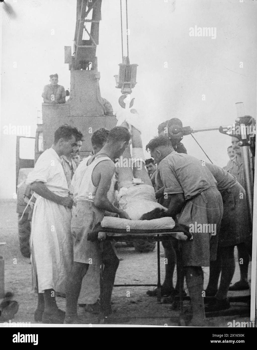BRITISH MEDICAL SERVICES IN THE SECOND WORLD WAR - The Medical Chain of Evacuation: Emergency surgery on a soldier with a broken spine at a Field Dressing Station (FDS) in the Western Desert. A mobile crane is being used to lift the man into the correct position before a plaster cast can be applied British Army Stock Photo