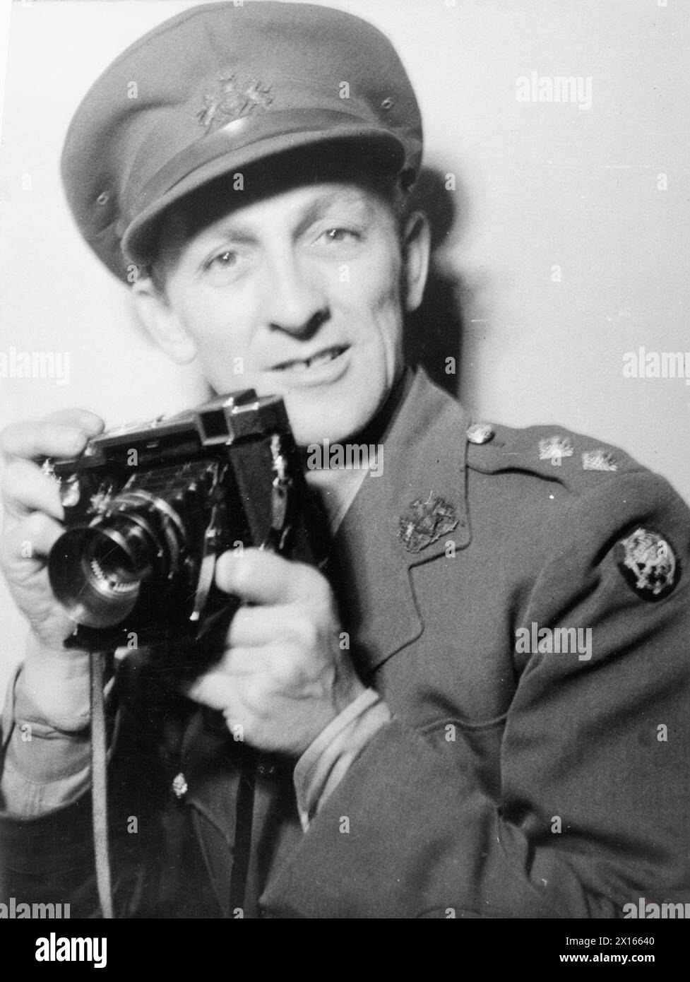 THE LIFE AND WORK EDWARD G MALINDINE, PHOTOJOURNALIST AND OFFICIAL ARMY PHOTOGRAPHER 1906 - 1970 - Lt Edward G Malindine, official photographer with the War Office Directorate of Public Relations, holding a Zeiss Icon Super Ikonta camera, March 1941. The camera replaced the First World War era Goerz Anschutz as the Army official issue camera at the time of the founding of the Army Film & Photographic Unit. During 1941 - 1944, Malindine was responsible for covering British Army activities in UK Southern Command as well as special operations such as the Vaagso Raid British Army, Army Film and Ph Stock Photo