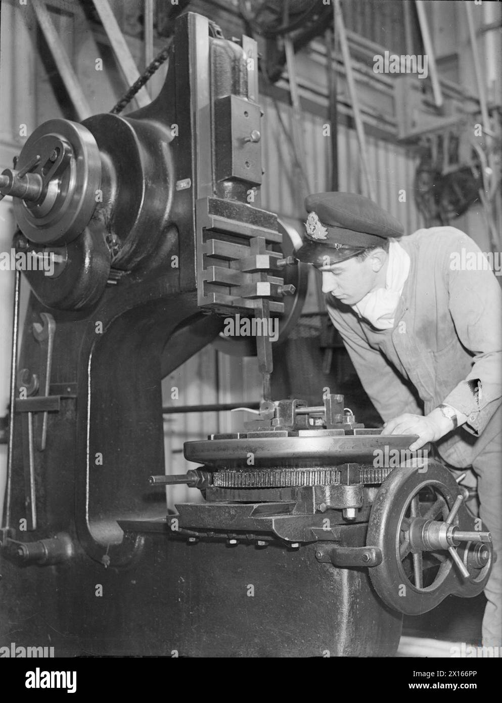 THE ROYAL NAVAL ENGINEERING COLLEGE, KEYHAM. 1941, THE COLLEGE TRAINS OFFICERS FOR THE ENGINEERING BRANCH OF THE ROYAL NAVY IN ALL ITS VITAL APPLICATIONS. - A midshipman cleaning up a casting on one of the machines in the fitting shop Stock Photo