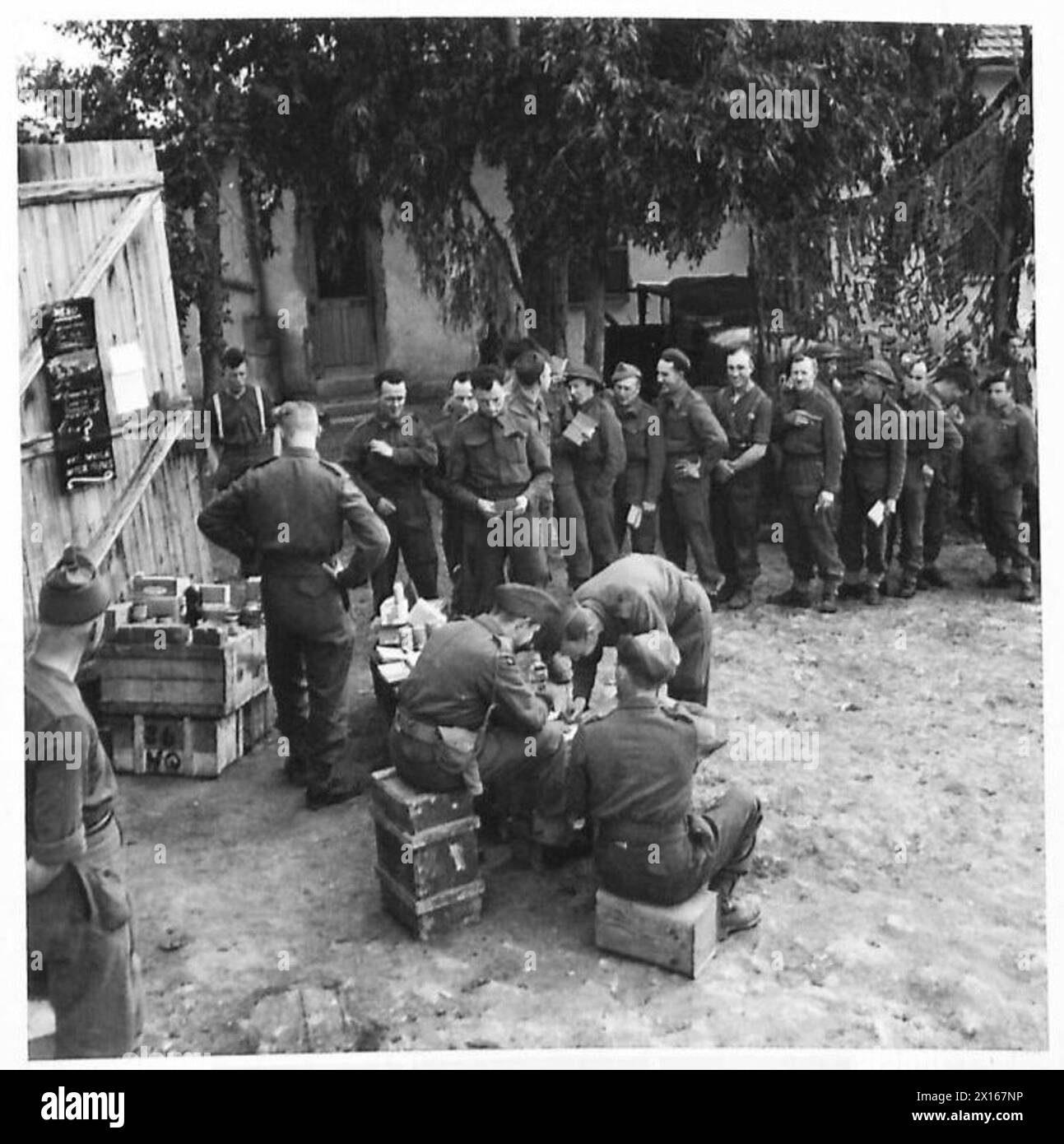 NAAFI SUPPLIES FOR FRONT LINE UNITS - Back at the unit. Troops line up to receive their weekly rations of chocolate, cigarettes and matches British Army Stock Photo