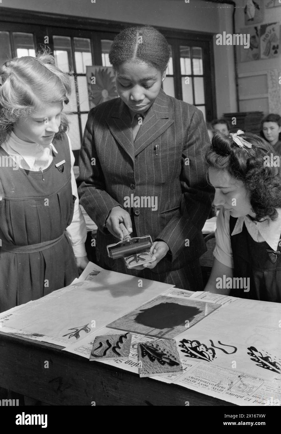 COLONIAL STUDENTS IN GREAT BRITAIN: STUDENTS AT UNIVERSITY OF LONDON INSTITUTE OF EDUCATION, LONDON, ENGLAND, UK, 1946 - Miss Kote-Amon from Labadi, Gold Coast, demonstrates the use of lino-cuts to senior girls at the Marlborough Senior Girls School, Isleworth, West London. She is a member of the staff of Kumasi Government School and has won the Gold Coast Teachers Certificate Stock Photo