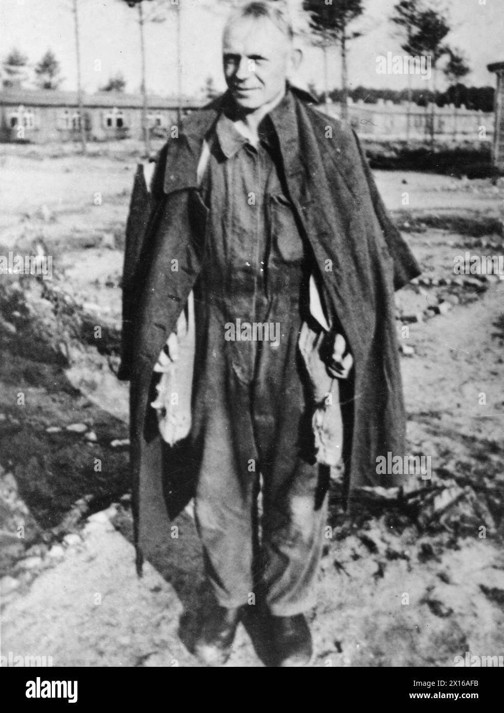 THE GREAT ESCAPE, MARCH 1944 - Sergeant-Major Hermann Glemnitz, the senior member of the German guard of the Stalag Luft III in Sagan, demonstrates the 'penguins' trouser legs for dispersing sand. The bags should be hanging inside the trouser legs, but he is wearing his 'ferret' overalls.Photograph probably taken just after Glemnitz had stumbled across the 'Tom' escape tunnel at Stalag Luft III, Sagan, September 1943 German Air Force, Glemnitz, Hermann Stock Photo