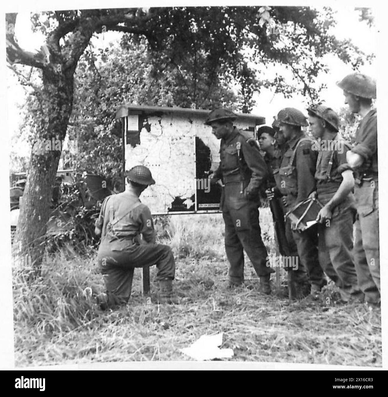 THE BRITISH ARMY IN NORTH-WEST EUROPE 1944-1945 - Men of the HQ of the 7th Bn. Green Howards are kept in touch with the war on all fronts by means of a notice board. Constantly on the move and always in forward areas, the notice board is soon erected and during a quiet spell the men keep in touch with the war news. Here are some of them studying a map of the battle front in the forward area British Army, 21st Army Group Stock Photo