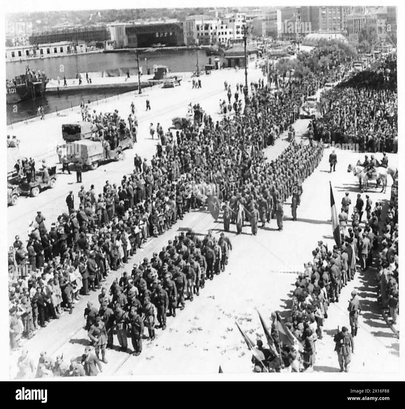A general view of a parade conducted by the British Eighth Army in liberated Trieste, showing troops, flags, and military vehicles. Stock Photo