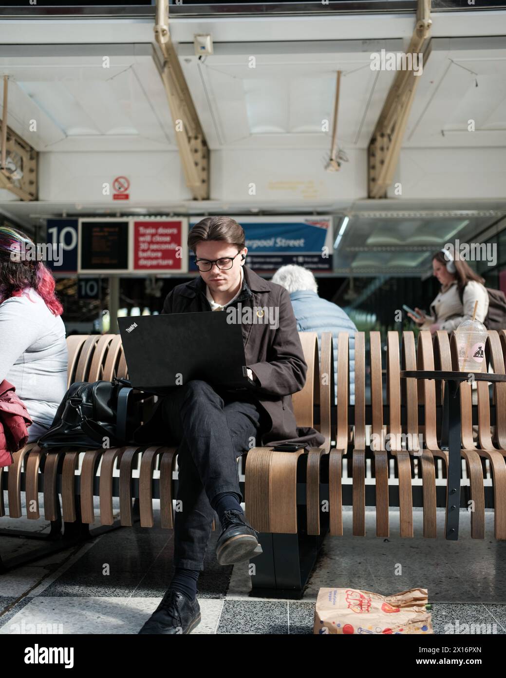 A man remote working in a train waiting room Stock Photo