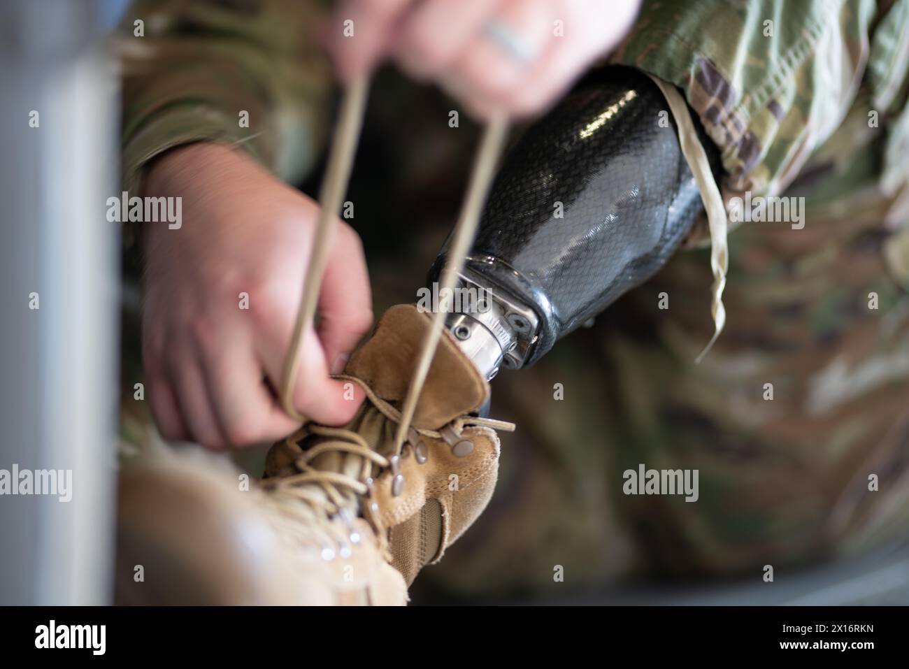 A man with a prosthetic leg is tying his shoe. Concept of resilience and determination, as the man is adapting to his new circumstances and continuing Stock Photo
