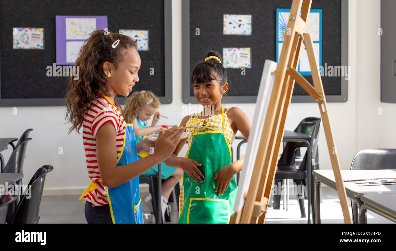 In school, in art class, a diverse group of young girls are painting Stock Photo