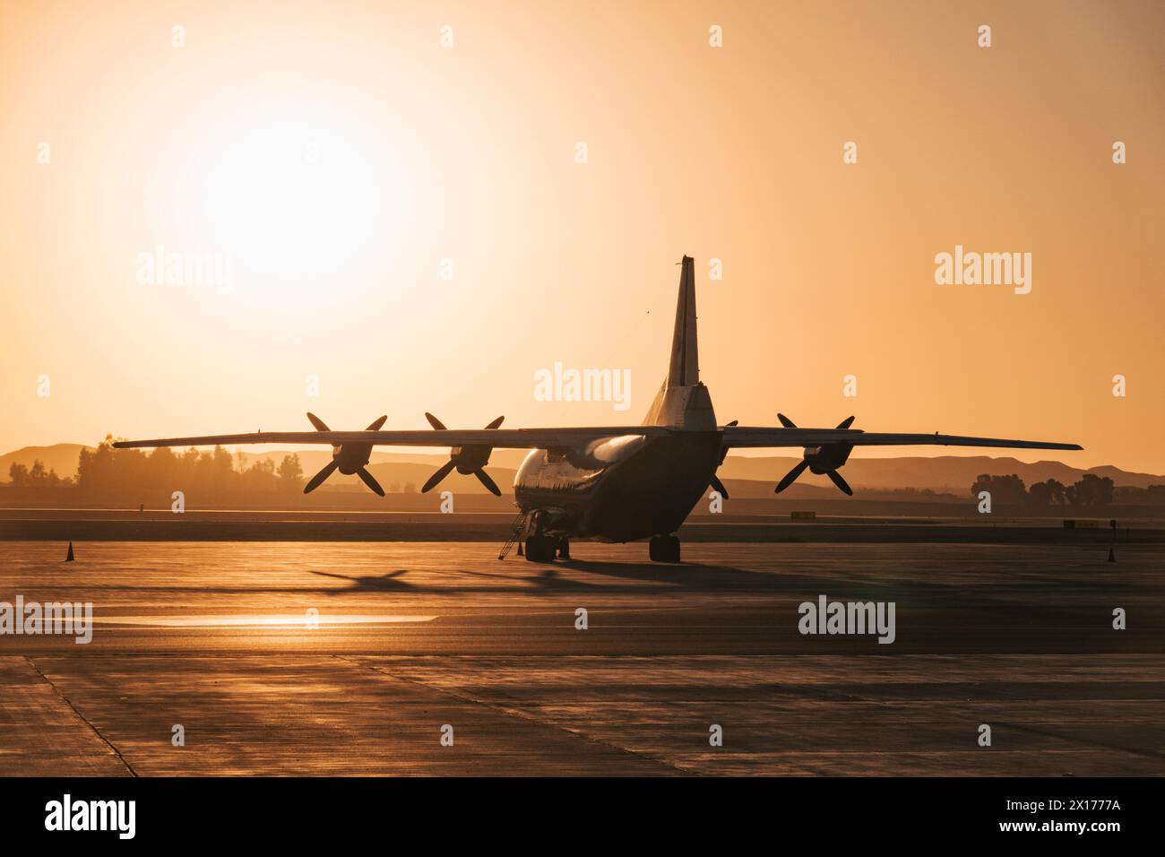 a Ukranian Antonov An-12 cargo plane of Motor Sich Airlines parked at Luxor Airport, Egypt, silhouetted against the morning sun Stock Photo