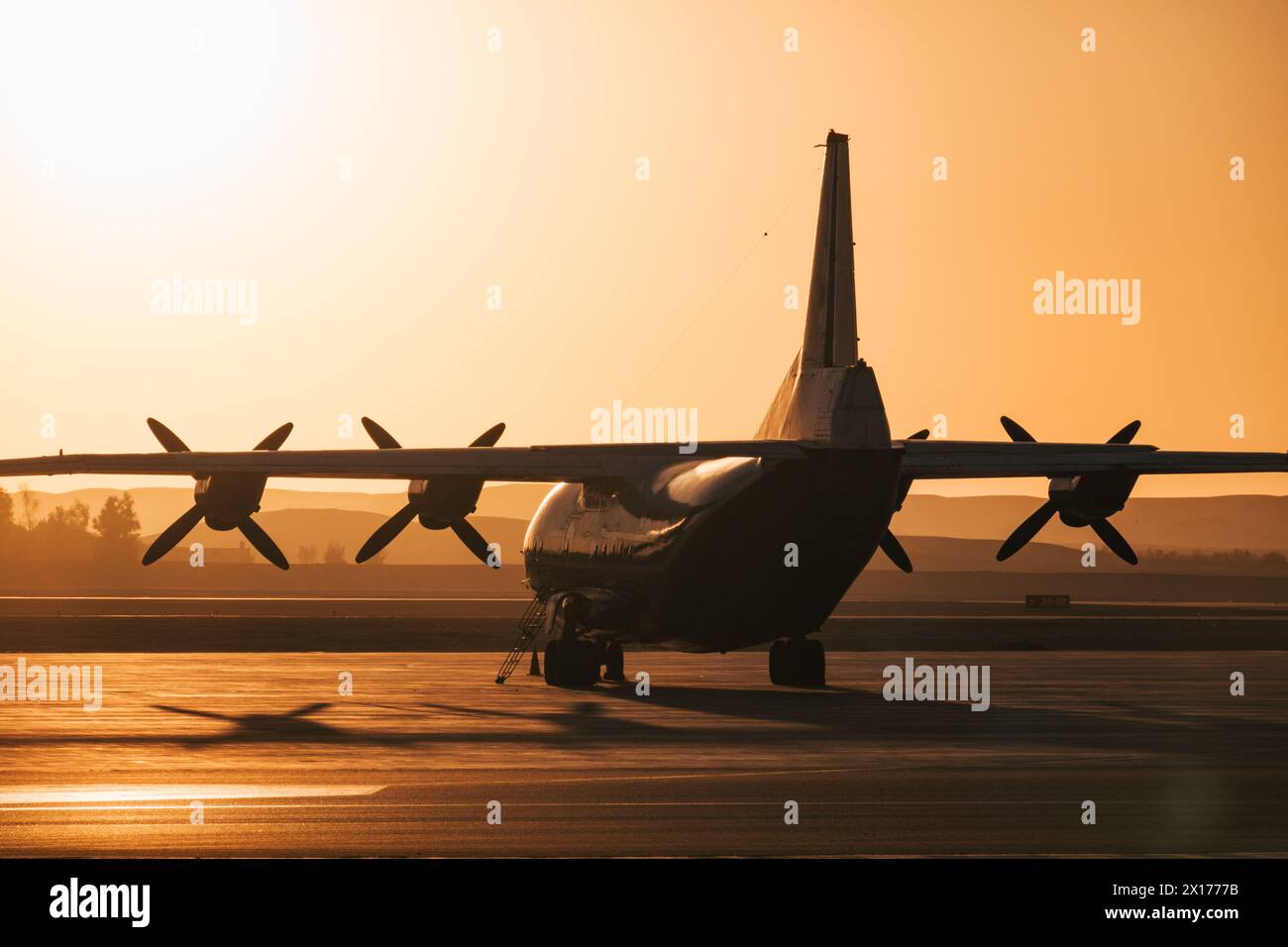 a Ukranian Antonov An-12 cargo plane of Motor Sich Airlines parked at Luxor Airport, Egypt, silhouetted against the morning sun Stock Photo