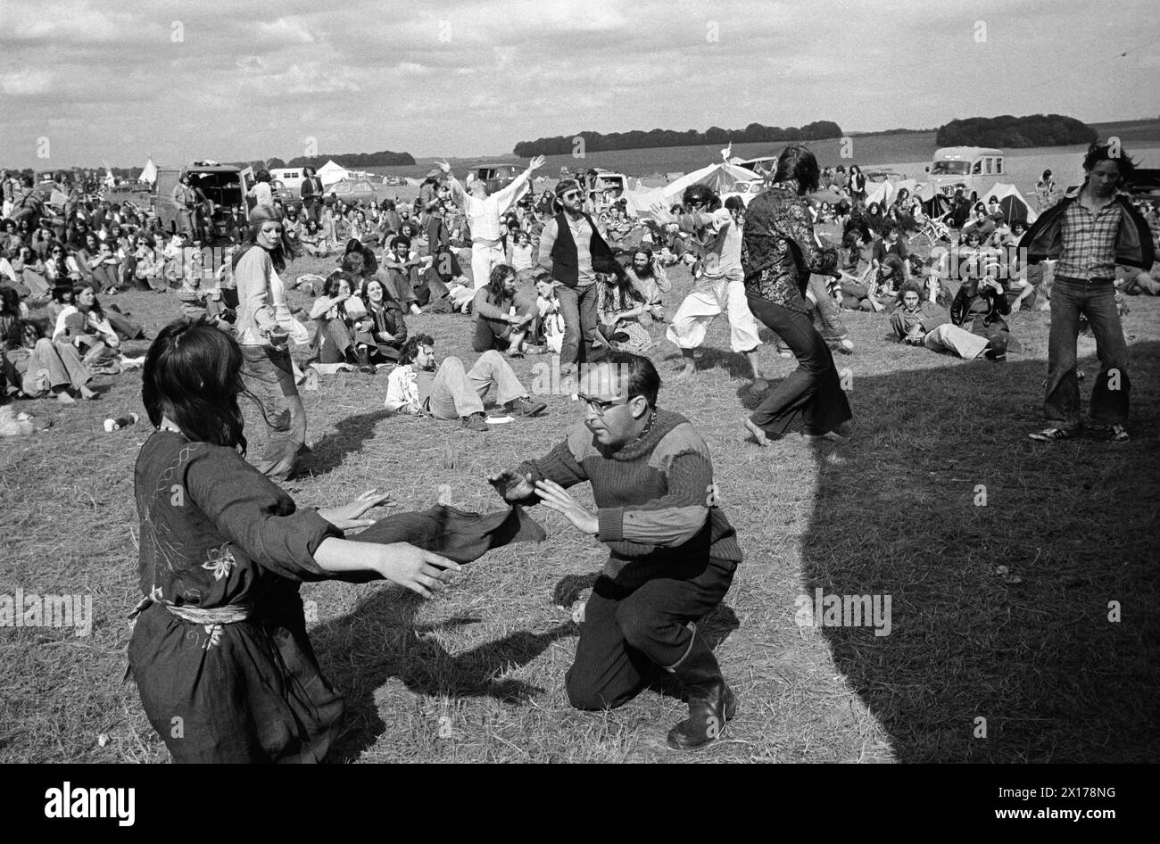 Festival goers dancing, others sitting around watching. Stonehenge Free Festival - Pop Festival - at the summer solstice, Wiltshire, England circa June 1976. 1970s UK HOMER SYKES Stock Photo