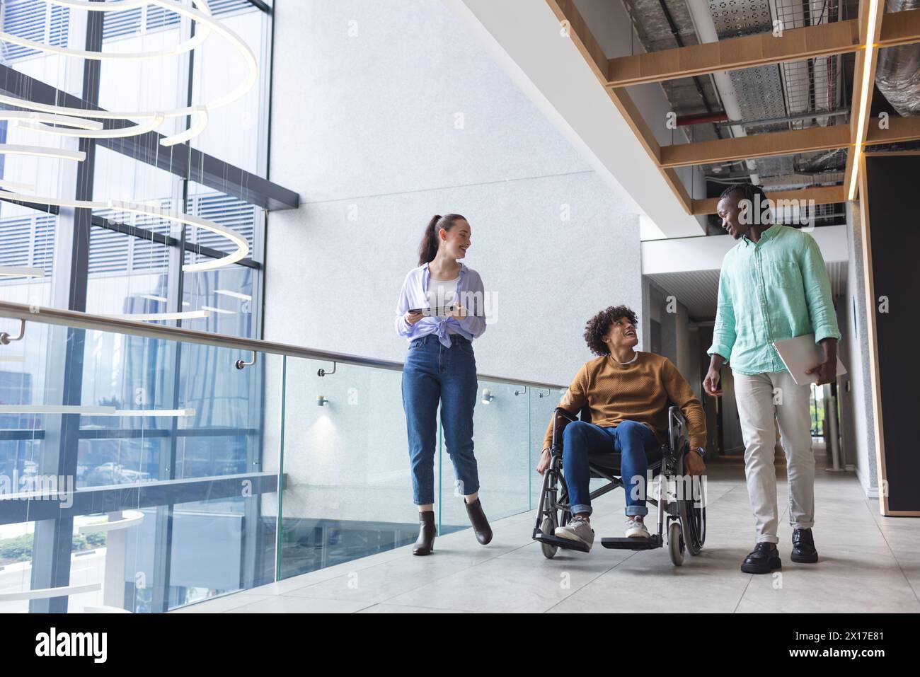Diverse group of friends walking and talking in modern hallway in a modern business office Stock Photo