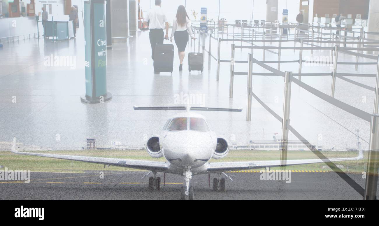 Composite image of plane at airport against businessman and businesswoman walking with trolley bags Stock Photo