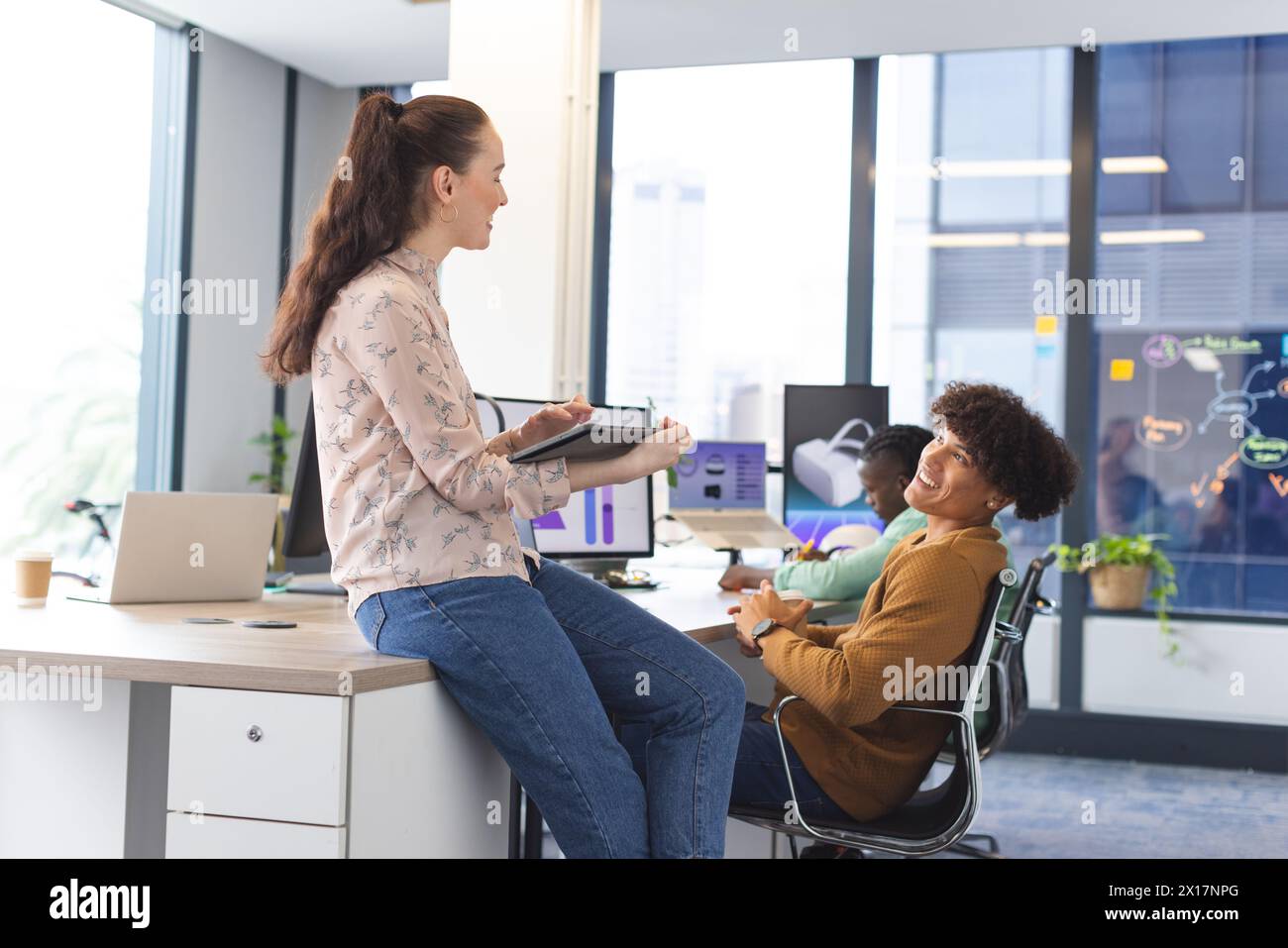 Diverse team discussing in office, Caucasian woman holding tablet Stock Photo