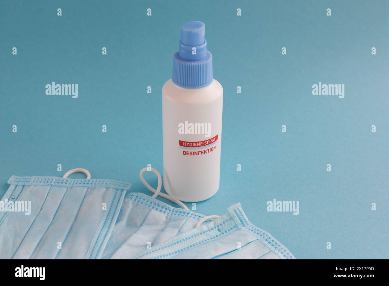 Desinfection spray and medical mask for hygiene on the blue background with place for text. Antibacterial, against pollution or virus protection. Covi Stock Photo