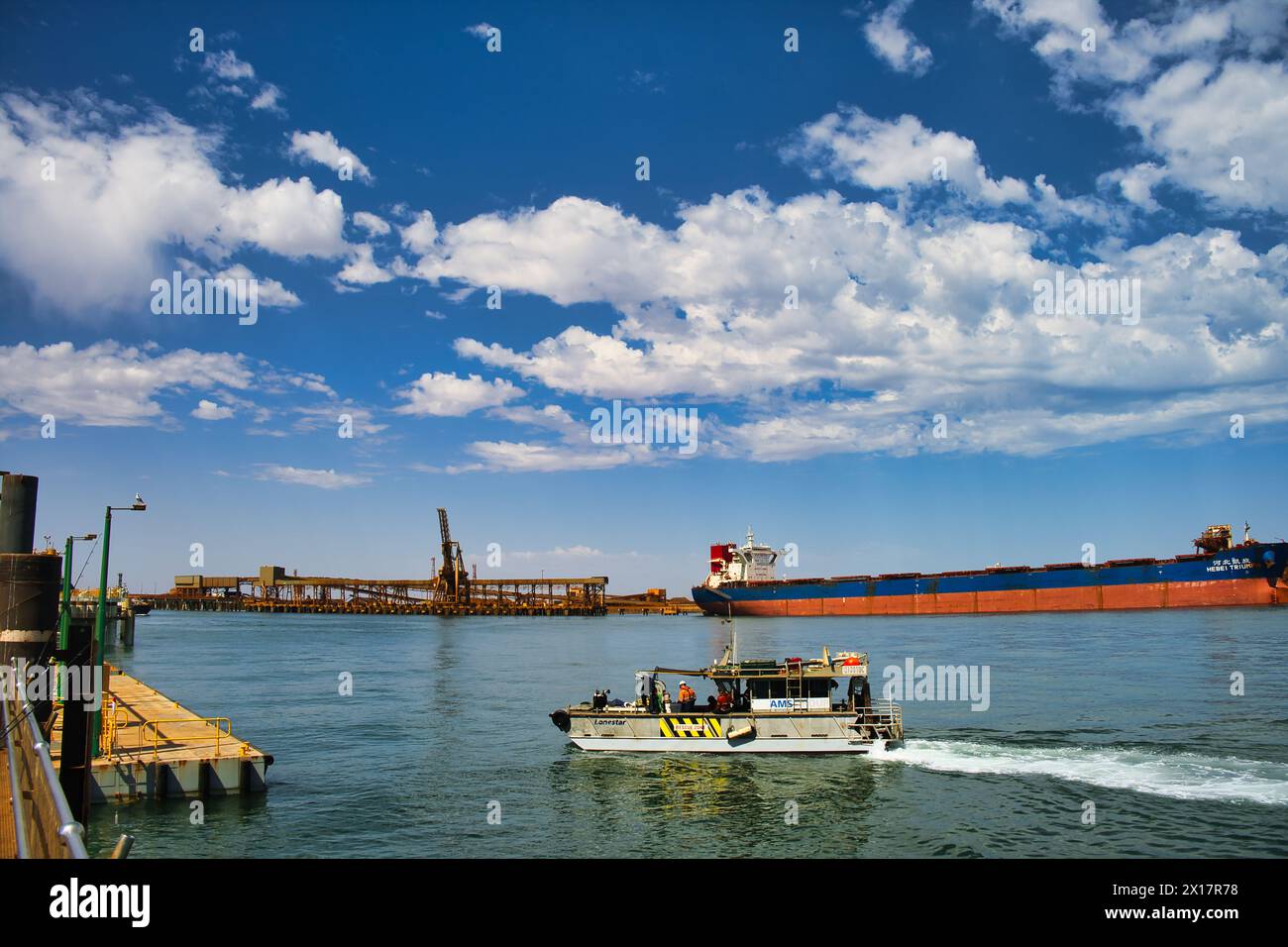 Pilot boat, Chinese bulk carrier and heavy duty harbour installations in the harbour of Port Hedland, in the northwest of Western Australia Stock Photo