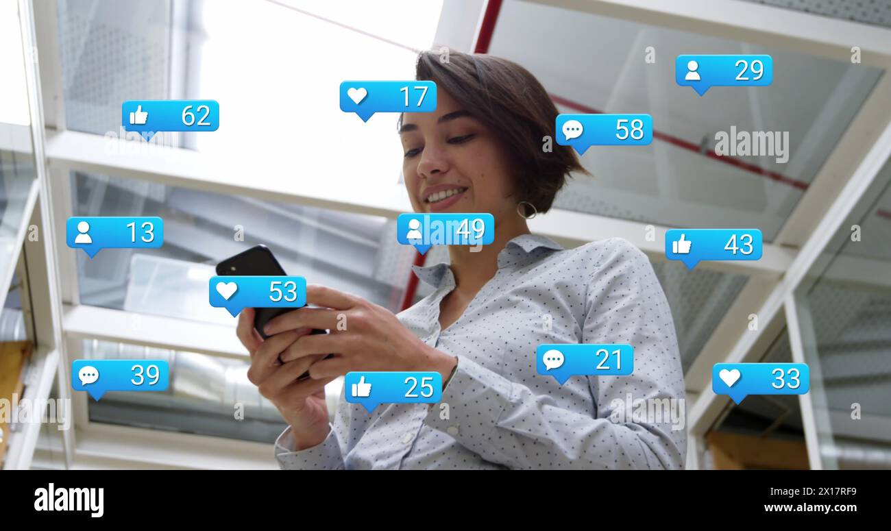 Image of social media icons with growing numbers over biracial businesswoman using smartphone Stock Photo