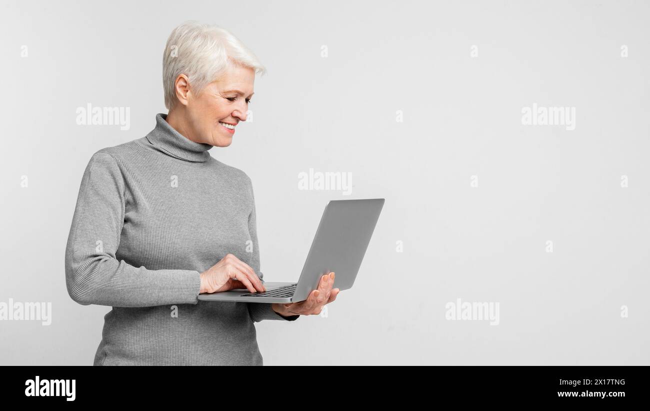 Happy mature woman typing on a laptop Stock Photo - Alamy