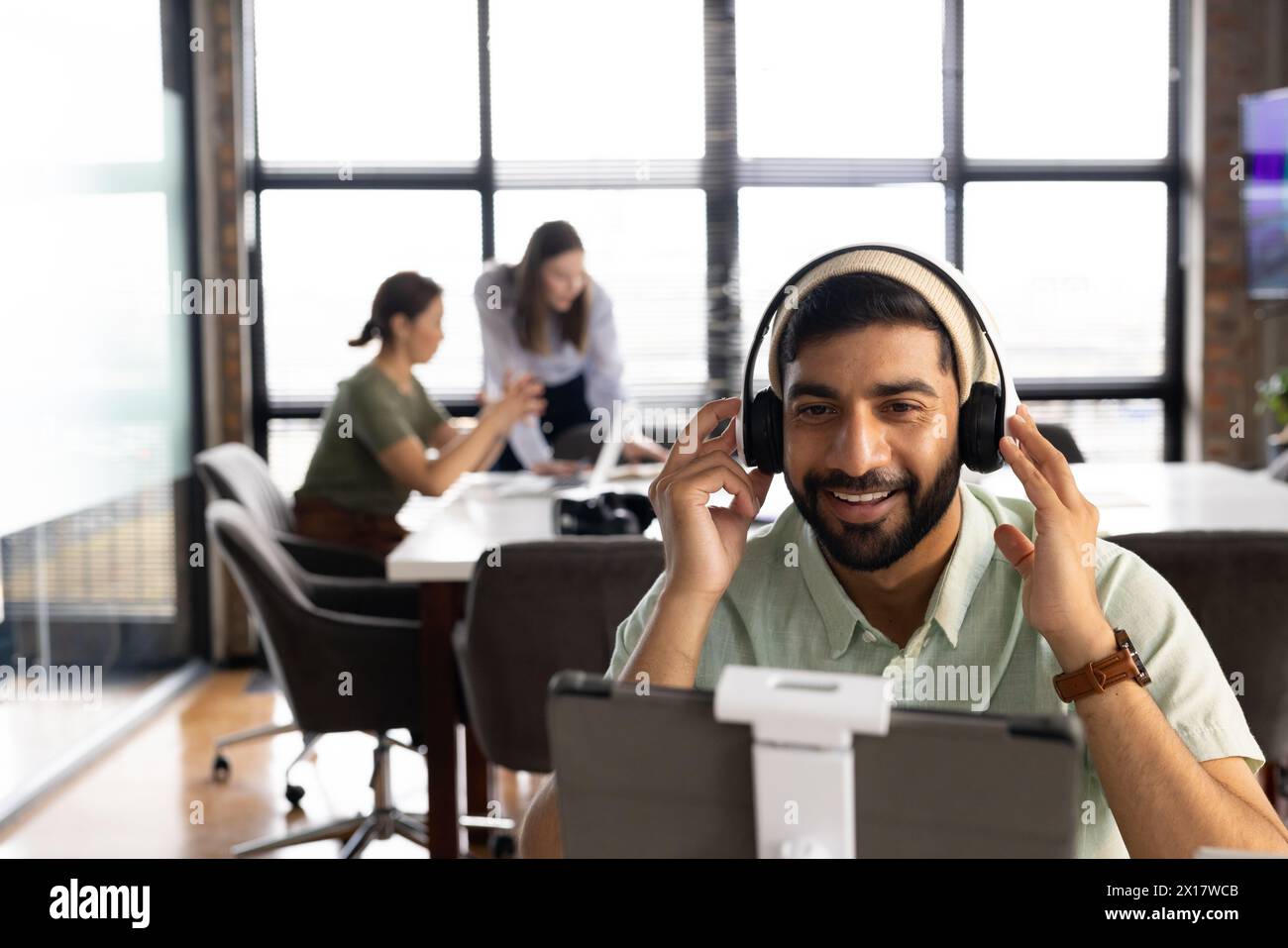 A diverse team working together in a modern business office, Asian male using tablet Stock Photo