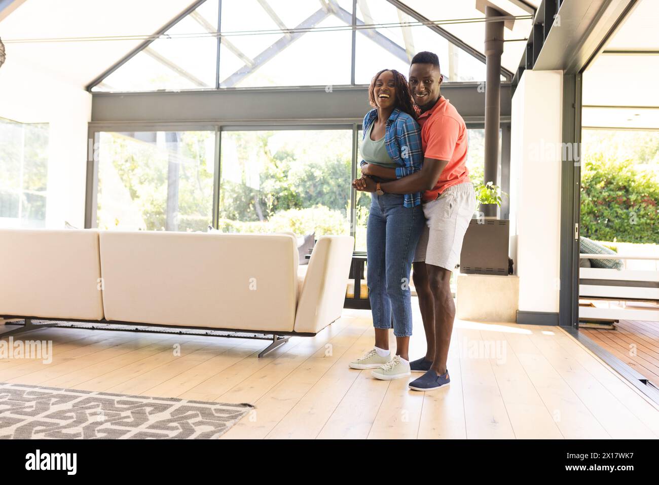 African American couple is embracing happily in a bright room at home with copy space Stock Photo