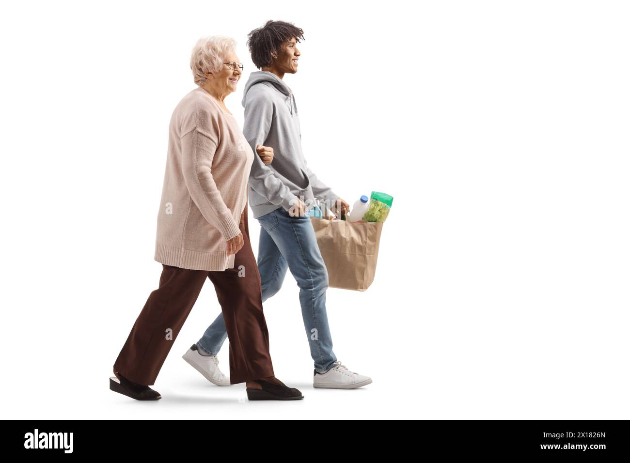 Young african american man walking with an elderly caucasian woman and carrying grocery bags isolated on white background Stock Photo