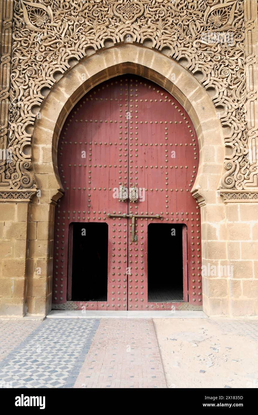 Meknes, entrance gate with filigree stucco ornaments, columns and tiled mosaics, Mulay Ismail mausoleum, Meknes, red wooden door with elaborate Stock Photo