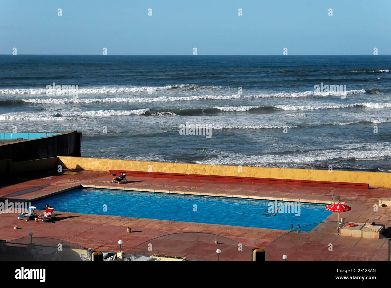 Essaouira, View of a swimming pool in front of the endless sea under a clear blue sky, Essaouira, Morocco Stock Photo