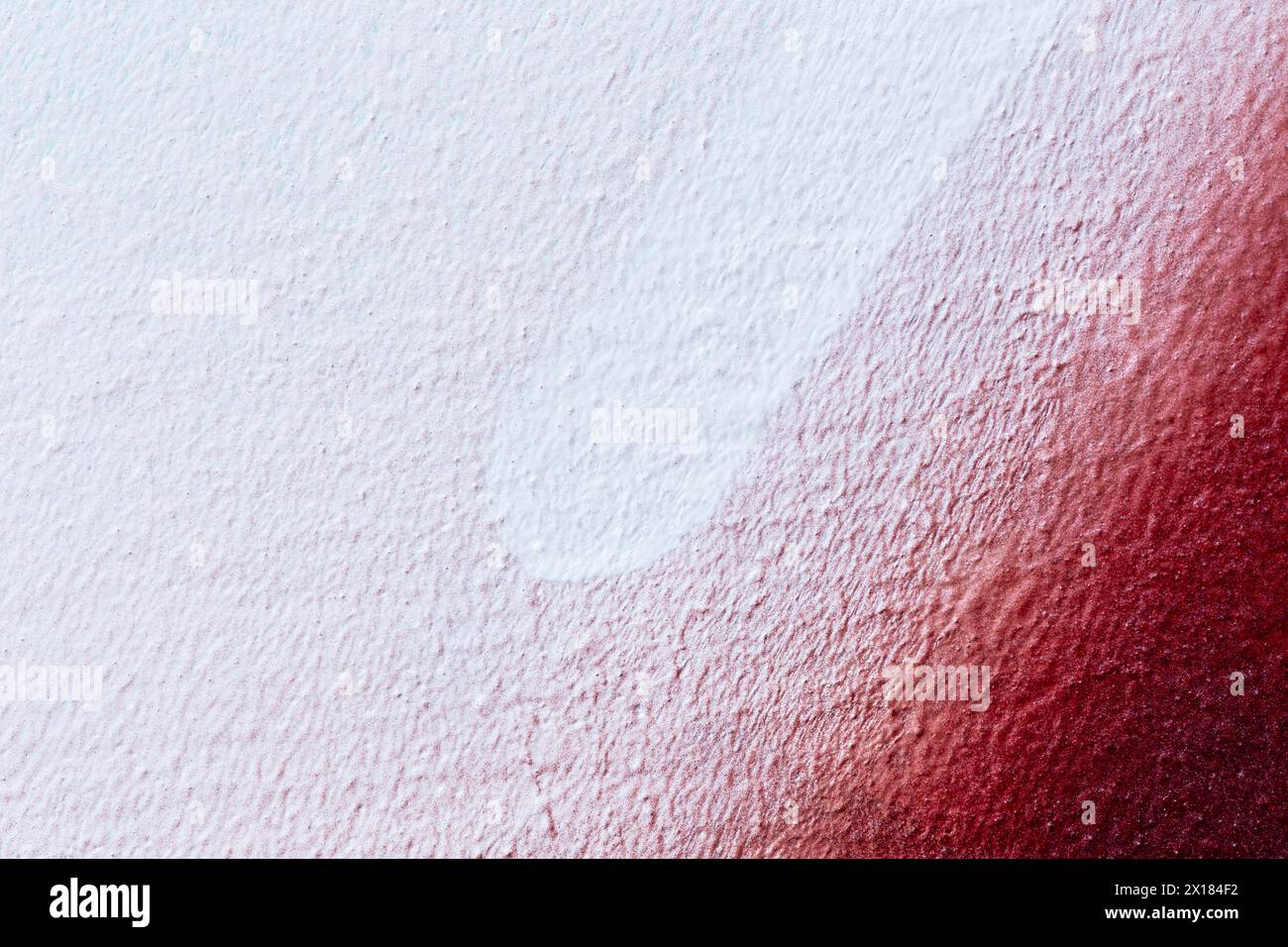 Macro close-up of a wall spray painted with white and red. Abstract full frame textured splattered graffiti background with copy space. Stock Photo