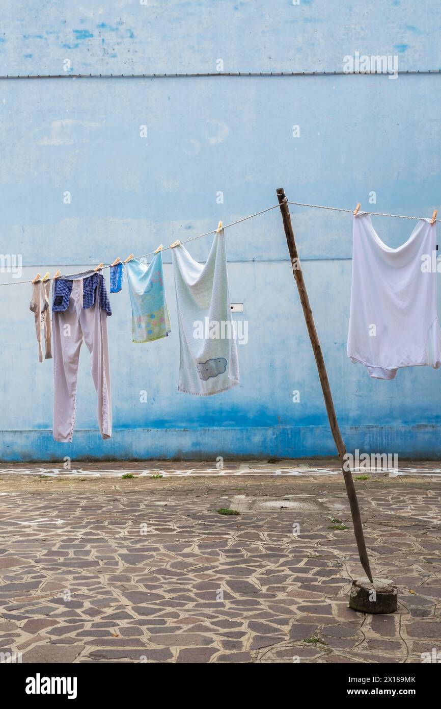 Washed clothes on clothesline in residential backyard with flagstones, Burano Island, Venetian Lagoon, Venice, Veneto, Italy Stock Photo