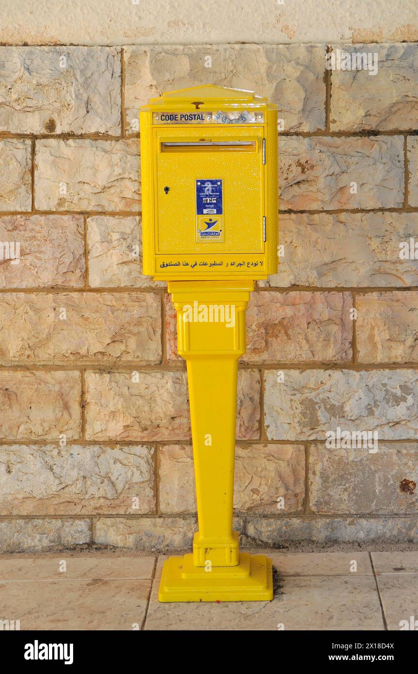 Fez, A yellow letterbox in front of a stone facade, a classic element of urban life, Northern Morocco, Morocco Stock Photo