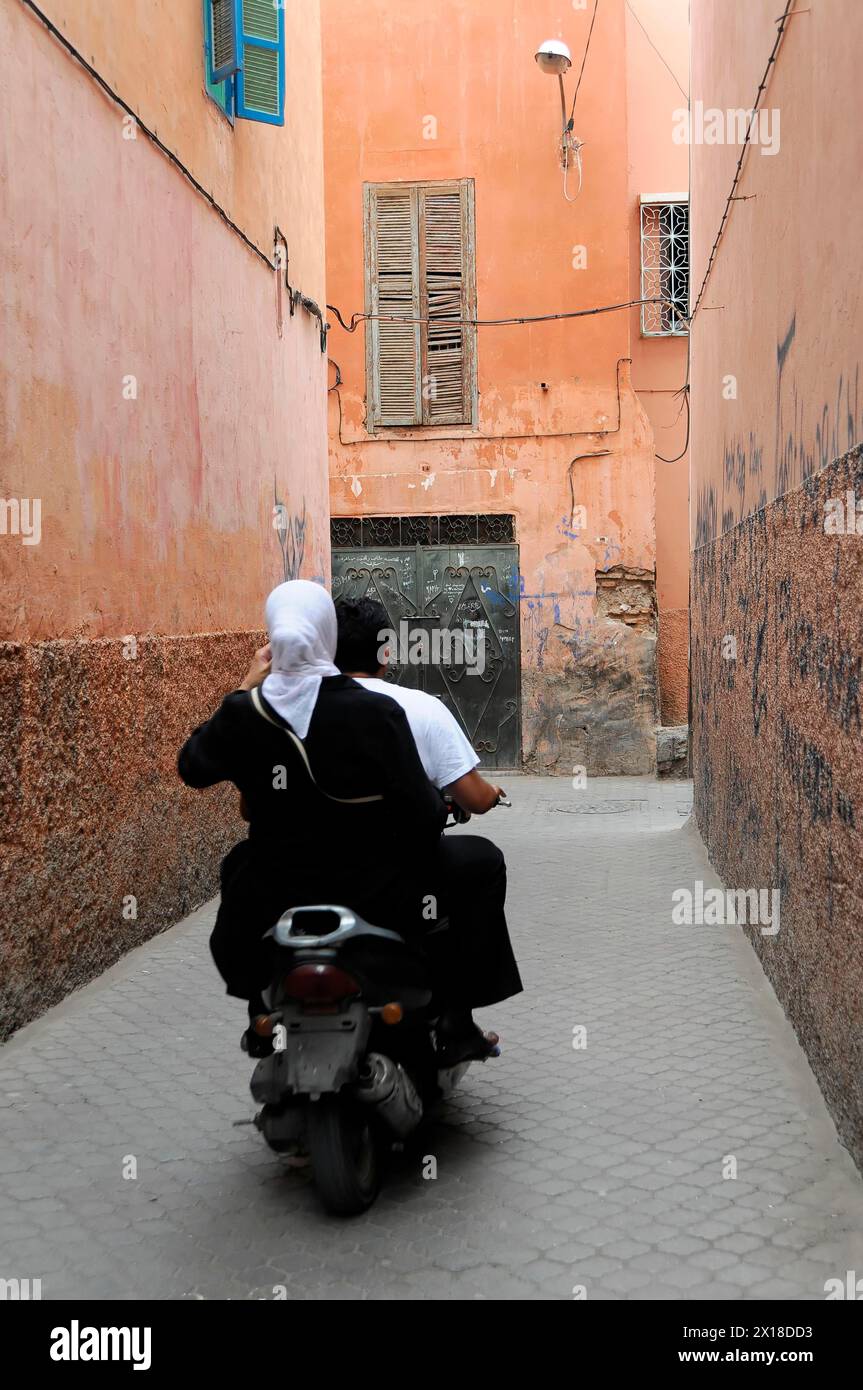 Marrakech, Narrow alley in a Moroccan city with scooters and passersby