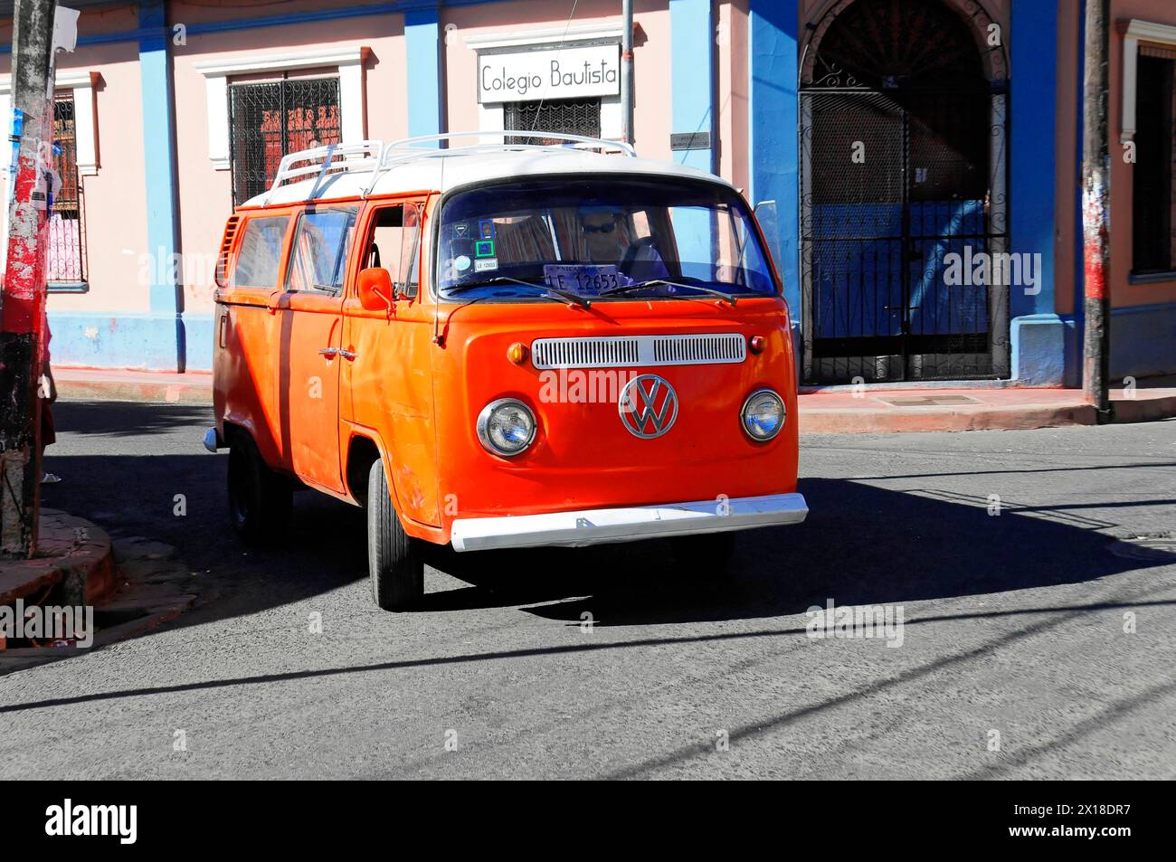 Leon, Nicaragua, A classic, orange-painted Volkswagen bus drives along a city street, Central America, Central America - Stock Photo