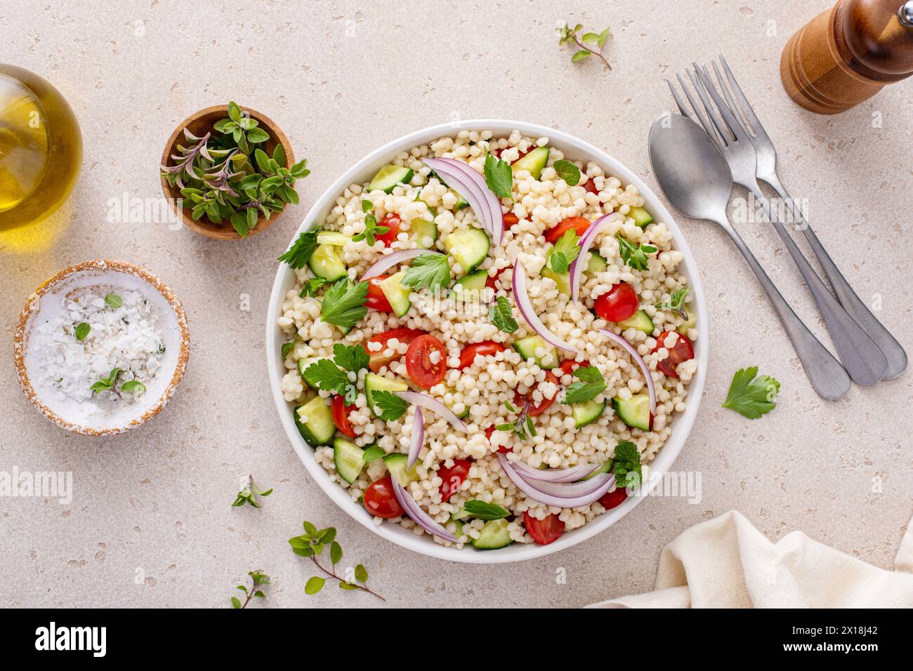 Pearl couscous salad with fresh vegetables and herbs in a serving bowl, healthy side dish idea Stock Photo