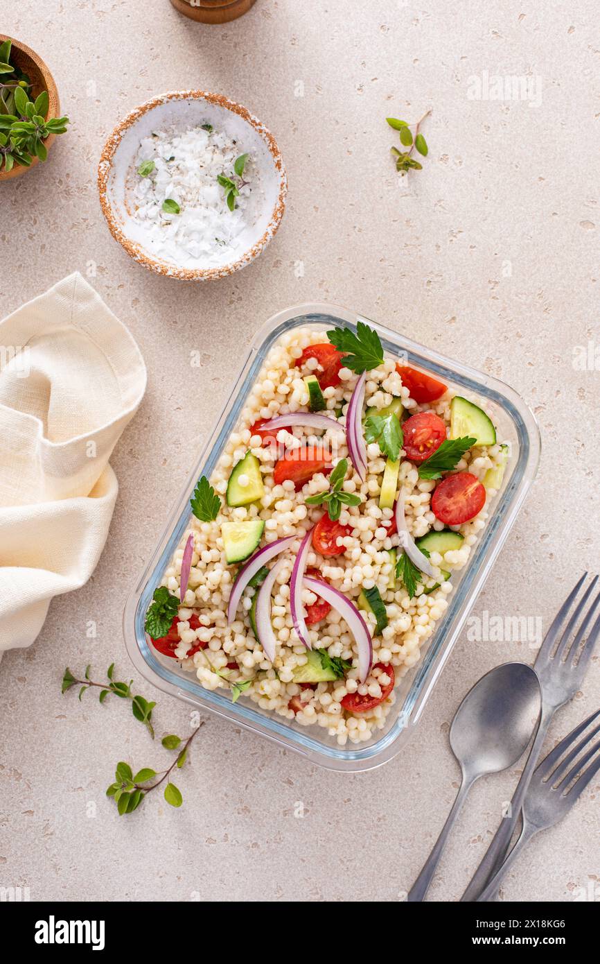 Pearl couscous salad with fresh vegetables and herbs in a meal prep container, healthy lunch or side dish idea Stock Photo