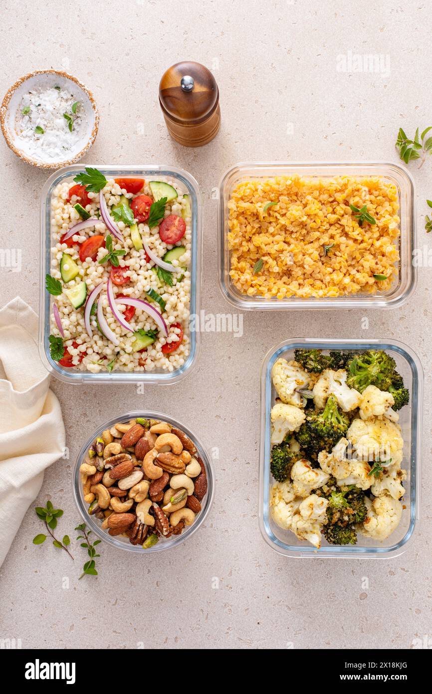 Healthy vegan meal prep with roasted vegetables, cooked lentils, couscous salad and mixed nuts Stock Photo