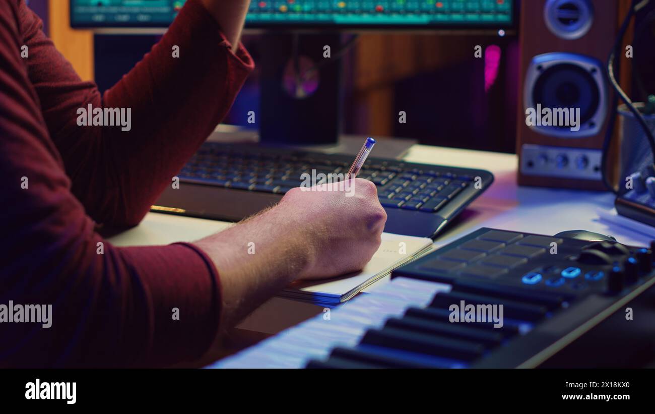 Composer developing an original track In his home studio, writing down