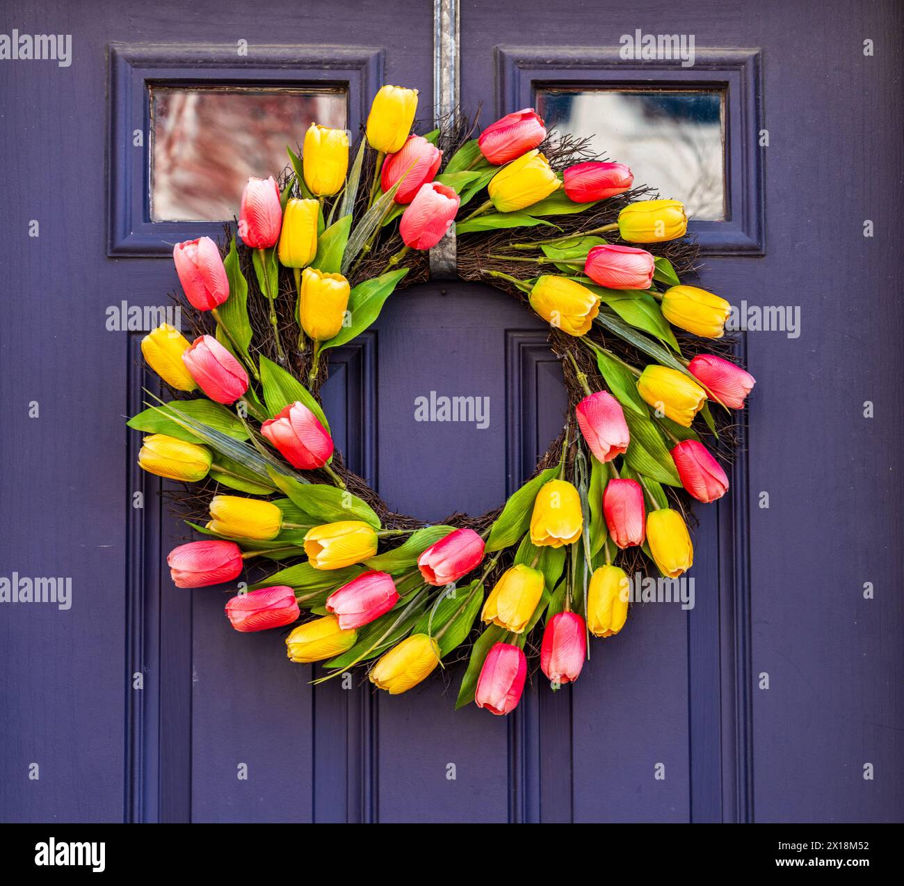 Arrangement of tulips in circular wreath on exterior door marking the start of Easter and springtime Stock Photo