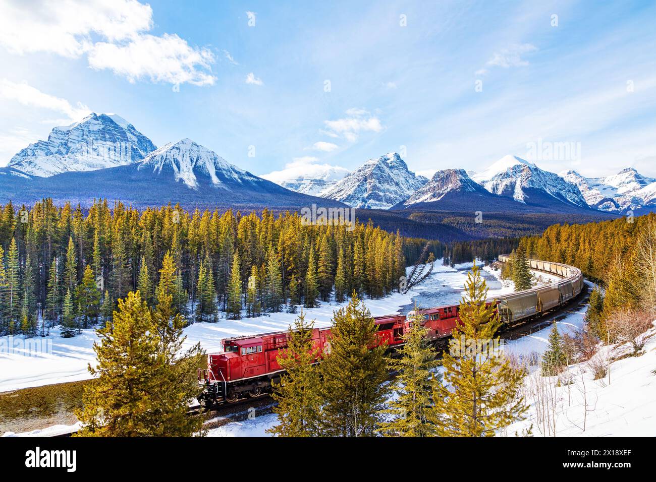 Red cargo train passing through Morant's curve in Bow Valley inside Banff National Park. Beautiful snowy winter landscape in the Canadian rockies of A Stock Photo