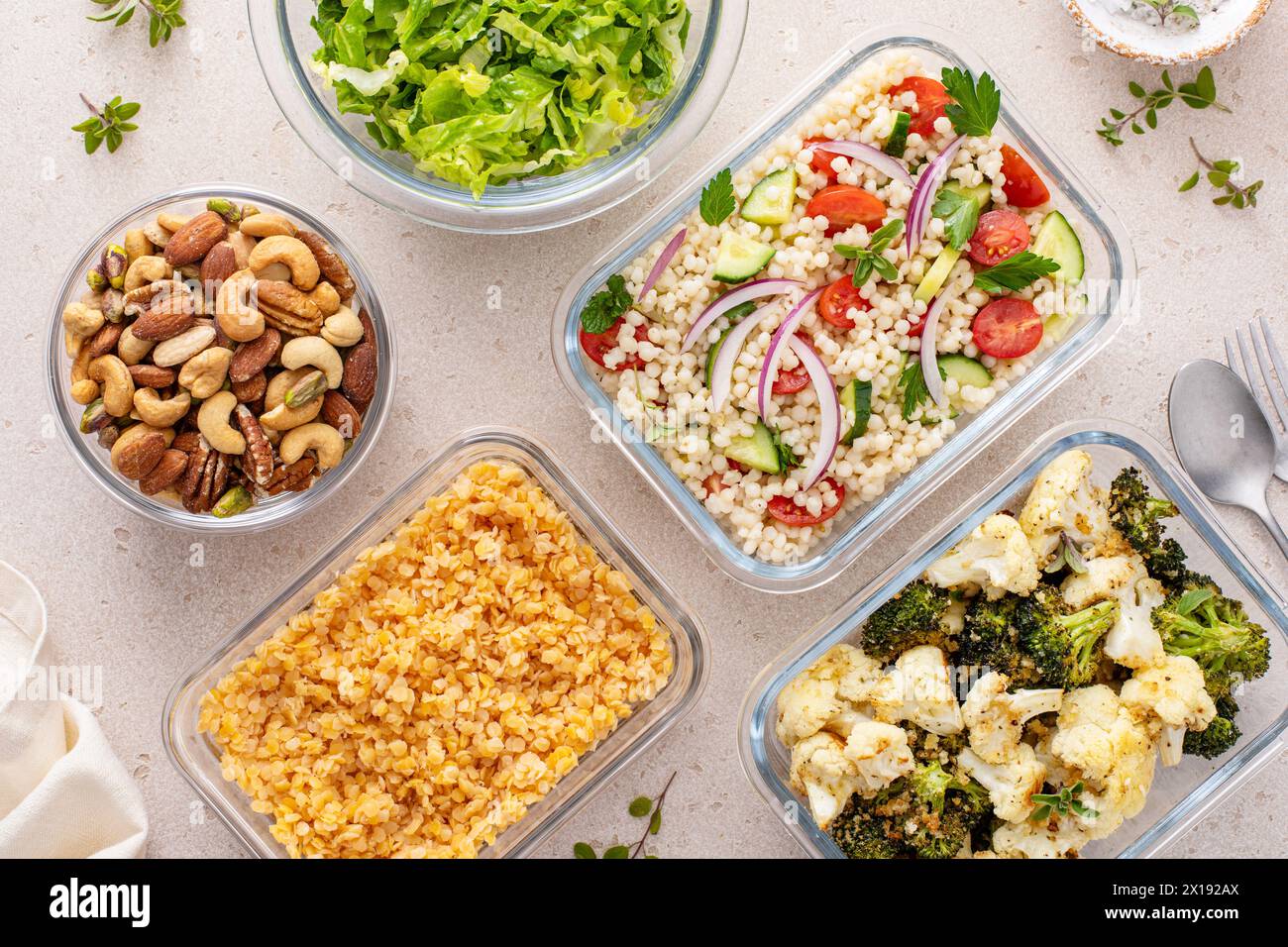 Healthy vegan meal prep with roasted vegetables, cooked lentils, couscous salad and mixed nuts Stock Photo