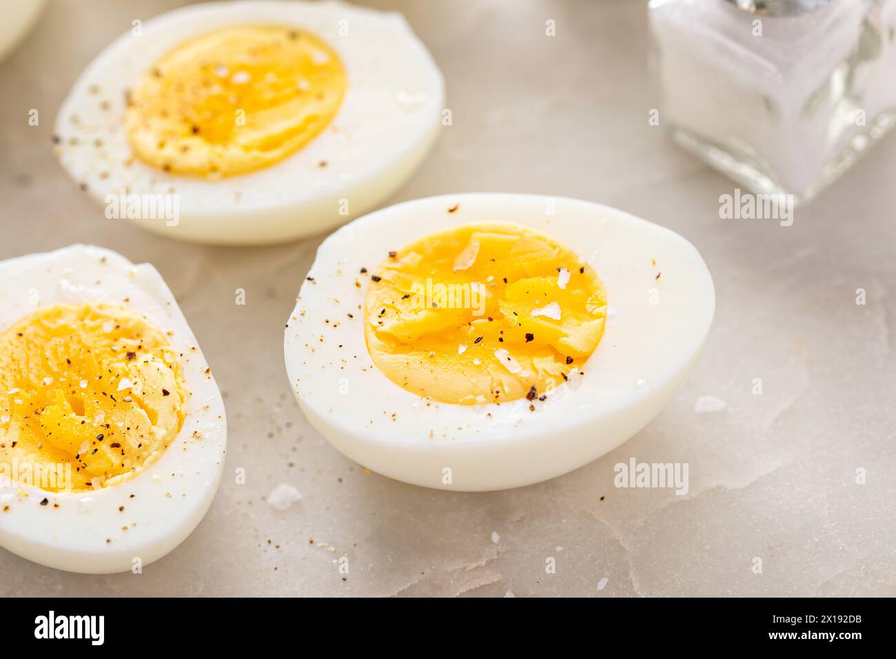 Hard boiled eggs peeled and cut in half with salt and pepper Stock Photo