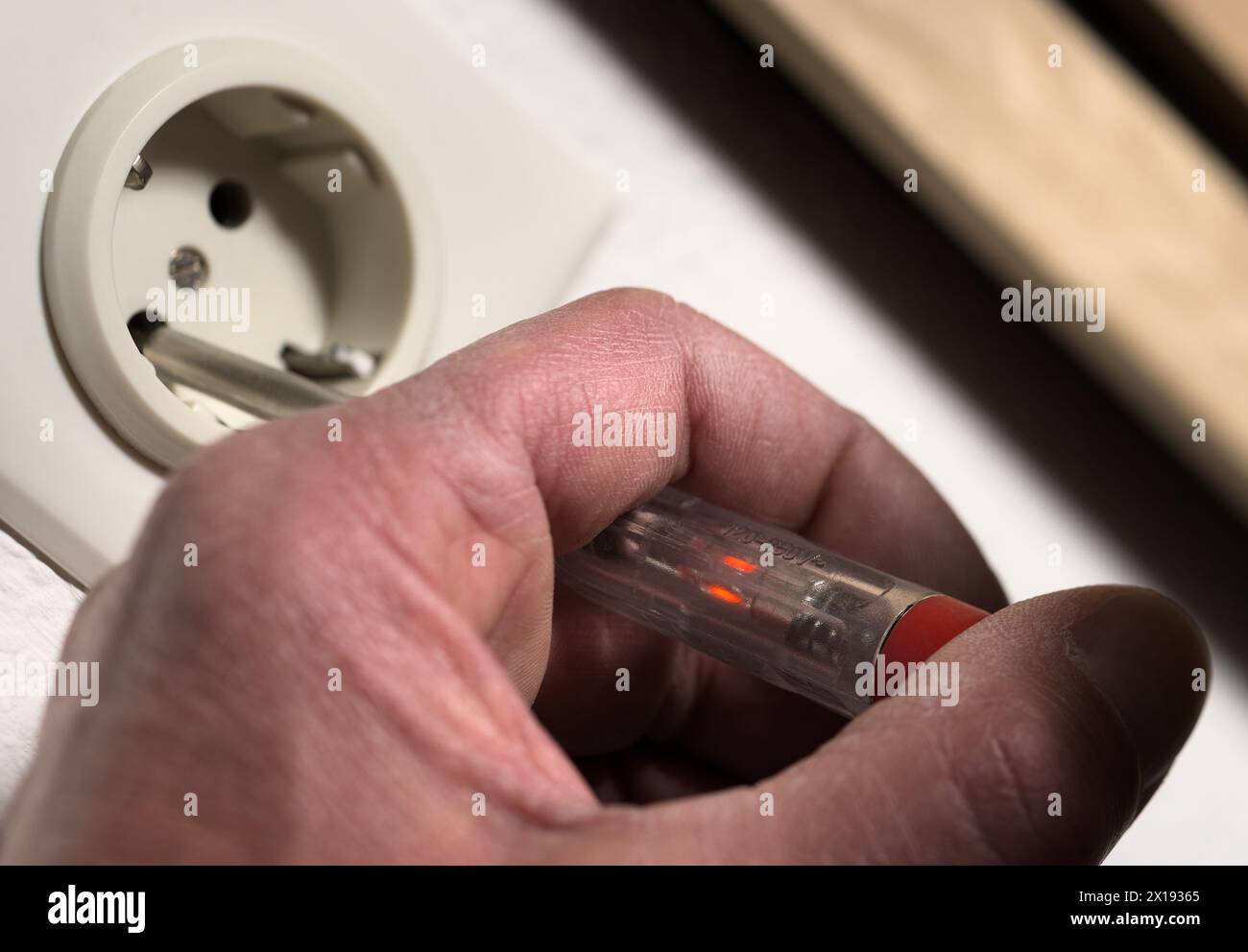 Checking mains grid voltage on wall power outlet socket with electrical circuit phase tester screwdriver Stock Photo