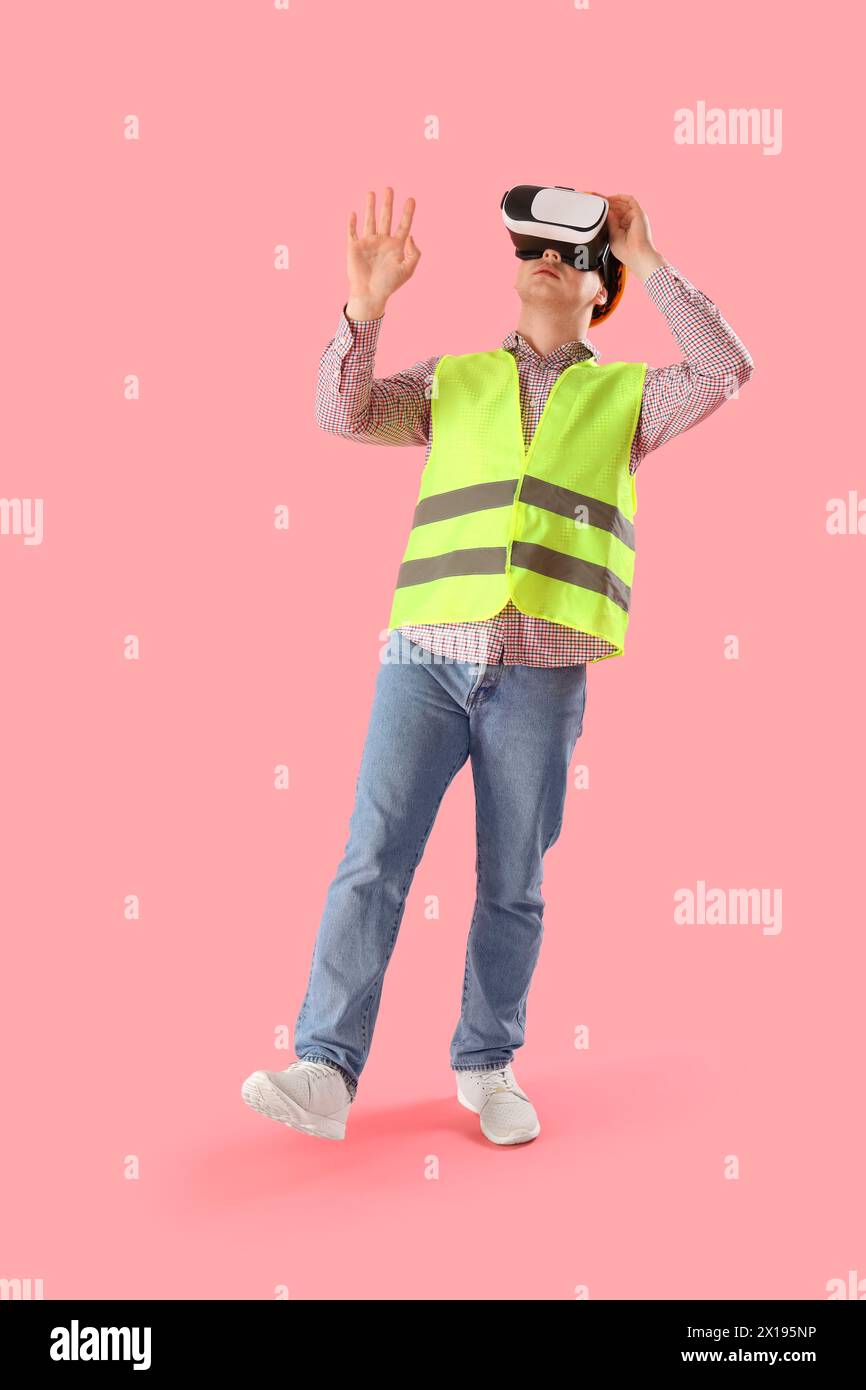 Male worker using VR glasses on pink background Stock Photo
