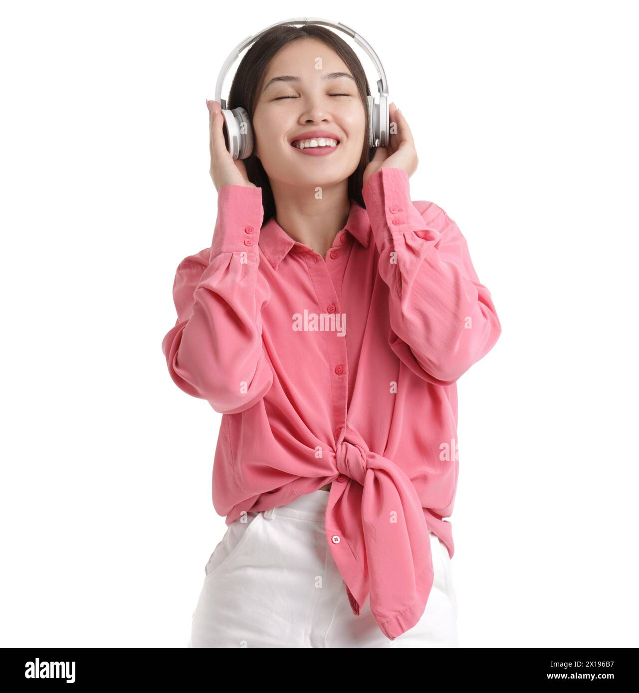 Young Asian woman in headphones listening to music on white background ...